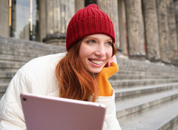 outdoor-shot-young-stylish-redhead-girl-sits-staircase-connects-public-wifi-uses-digita_1258-152054